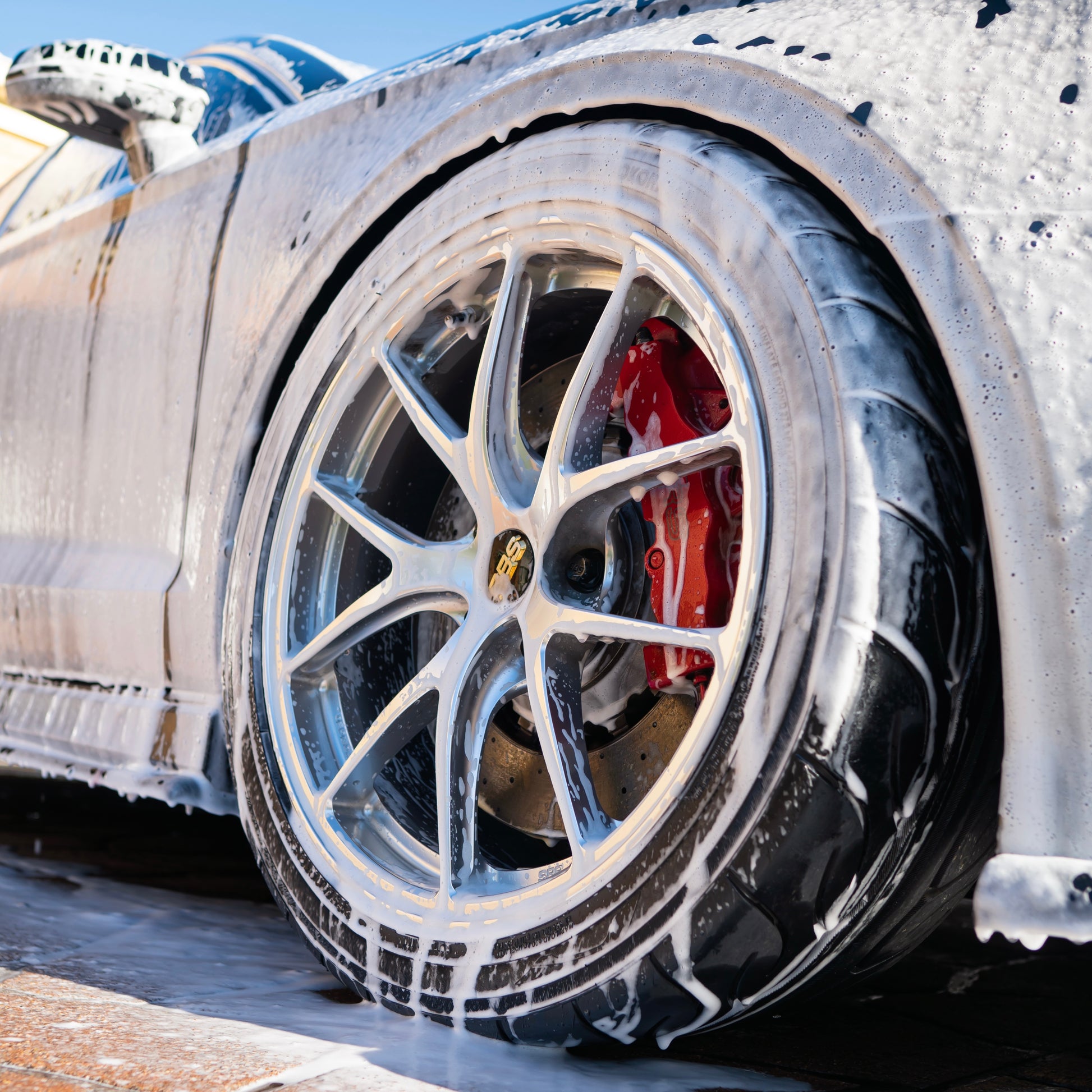 Close-up of a car tire with a detailed view of the rim and brake system, on a snowy background.